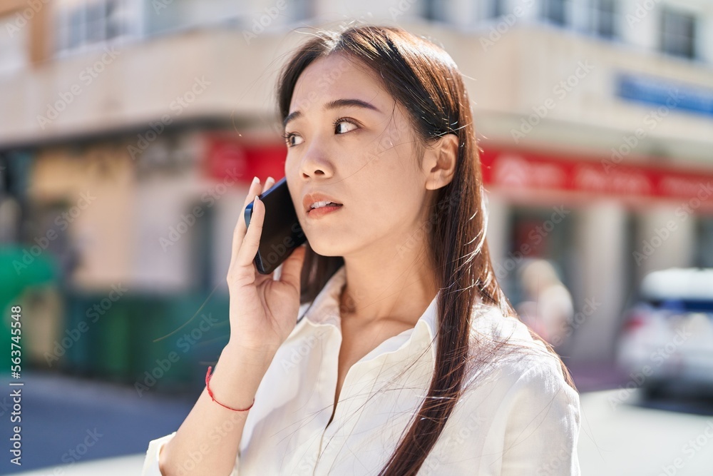 Young chinese woman talking on smartphone with serious expression at street Young chinese woman talking on smartphone with serious expression at street