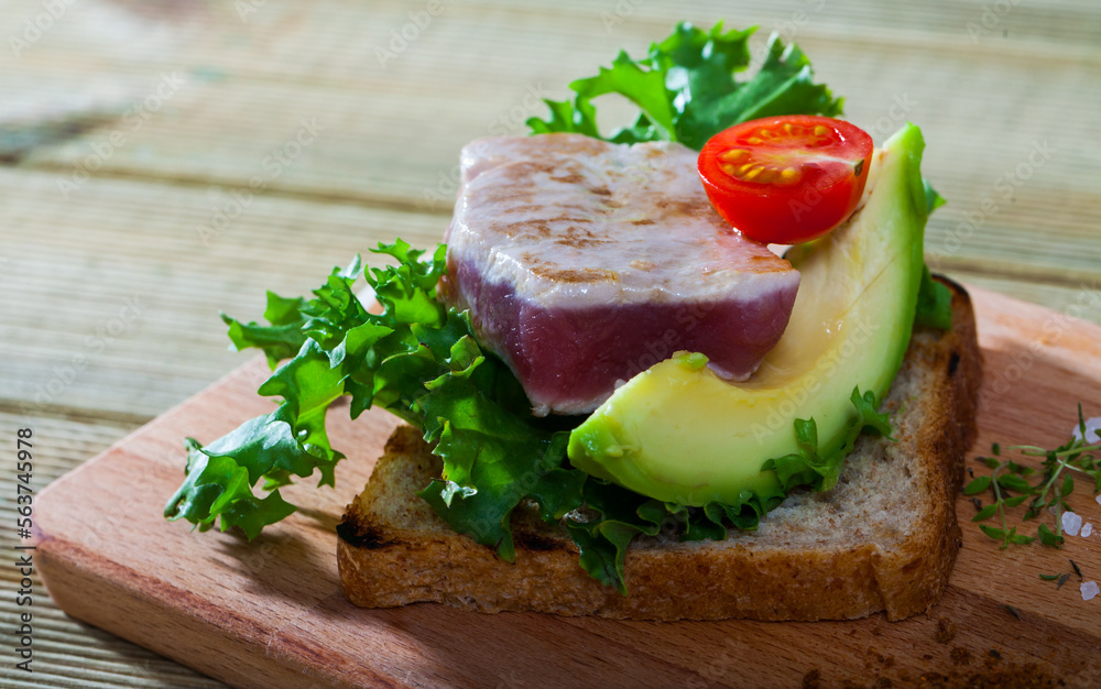 Toasted bread with tuna steak, salad, avocado and cherry tomato