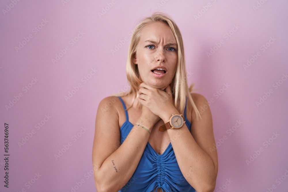 Young caucasian woman standing over pink background shouting suffocate because painful strangle. health problem. asphyxiate and suicide concept.