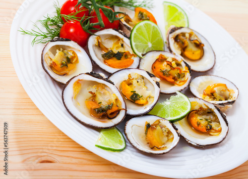 Baked Glycymeris glycymeris clams with sauce, served with lime