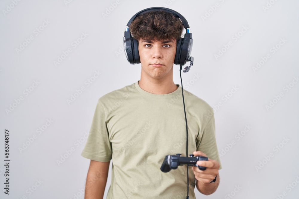 Hispanic teenager playing video game holding controller depressed and worry for distress, crying angry and afraid. sad expression.