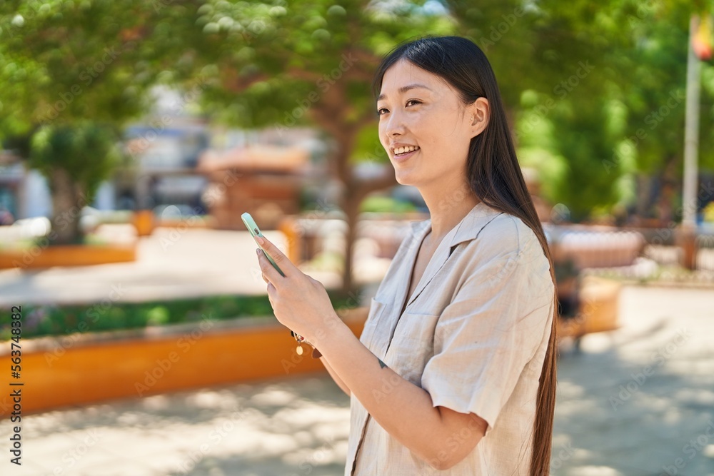 Chinese woman smiling confident using smartphone at park Chinese woman smiling confident using smartphone at park