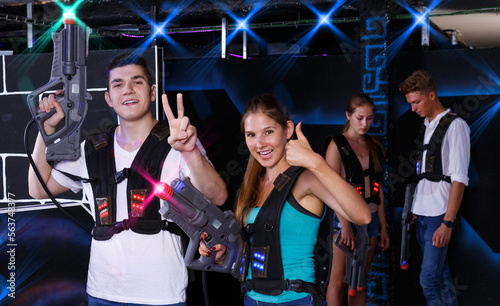 young guy and girl are happy with their victory in laser tag game in dark laser tag room