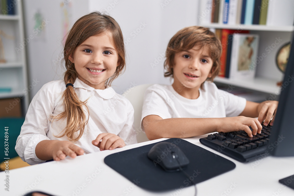 Brother and sister students using computer sitting on table at classroom Brother and sister students using computer sitting on table at classroom