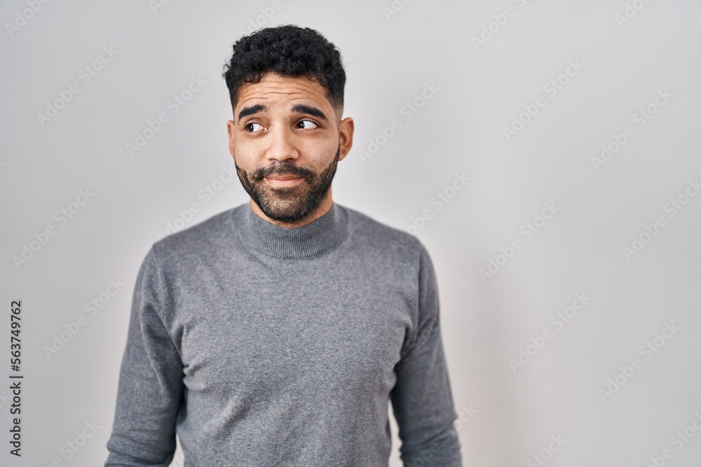 Hispanic man with beard standing over white background smiling looking to the side and staring away thinking. Hispanic man with beard standing over white background smiling looking to the side and staring away thinking.
