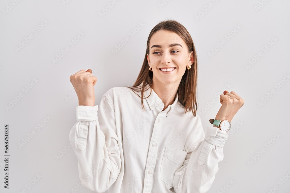 Young caucasian woman standing over isolated background celebrating surprised and amazed for success with arms raised and eyes closed. winner concept. Young caucasian woman standing over isolated background celebrating surprised and amazed for success with arms raised and eyes closed. winner concept.