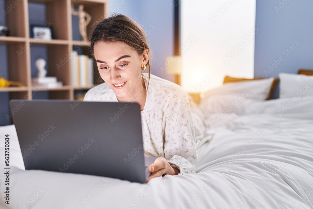Young caucasian woman using laptop lying on bed at bedroom Young caucasian woman using laptop lying on bed at bedroom