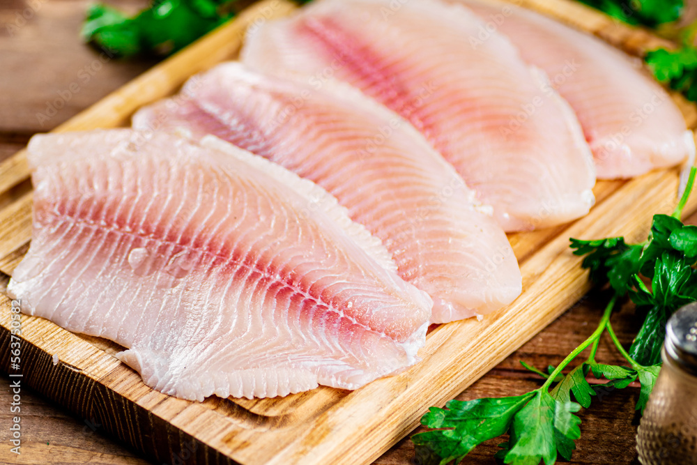 Raw fish fillet with parsley on a cutting board. Raw fish fillet with parsley on a cutting board.