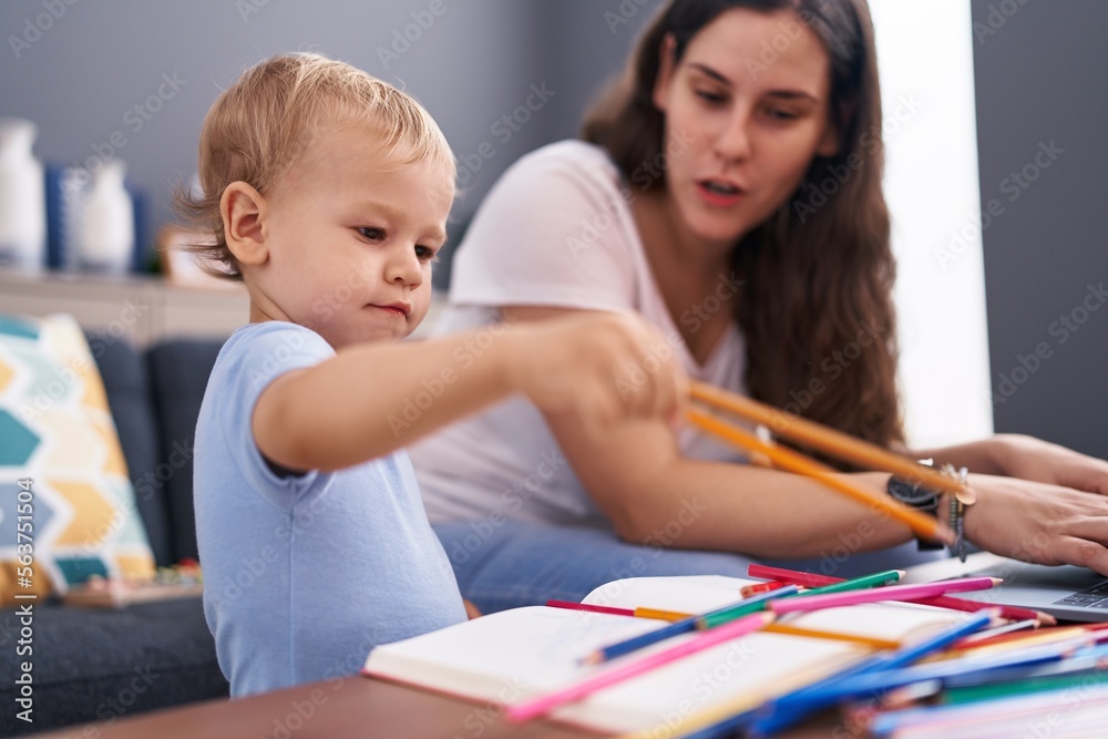 Mother and son drawing on notebook using laptop at home