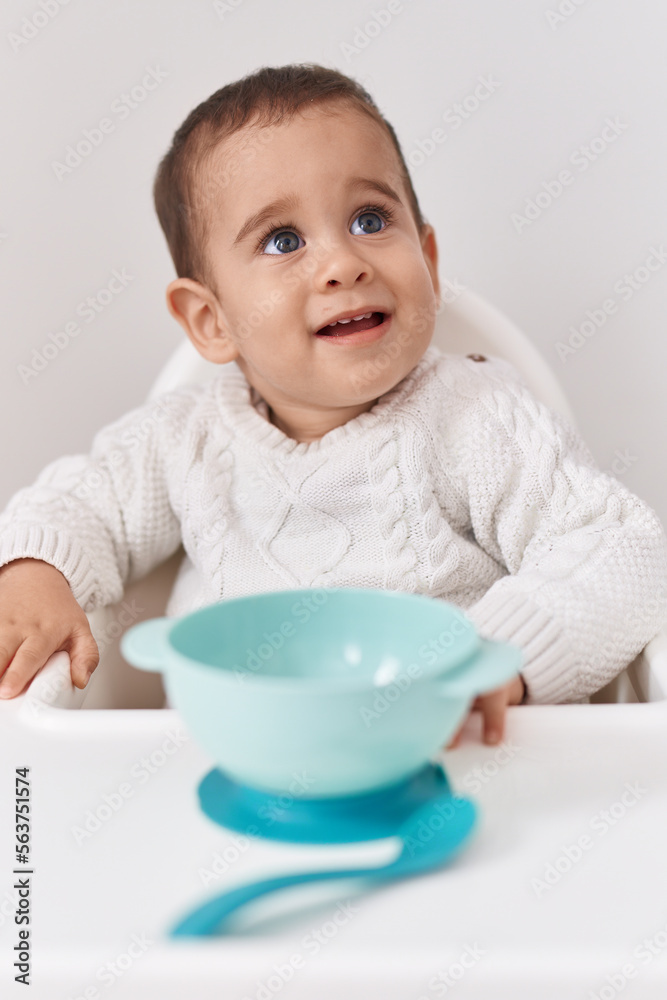 Adorable hispanic toddler smiling confident sitting on highchair over isolated white background Adorable hispanic toddler smiling confident sitting on highchair over isolated white background