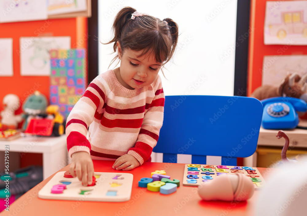 Fototapeta premium Adorable hispanic girl playing with maths puzzle game standing at kindergarten