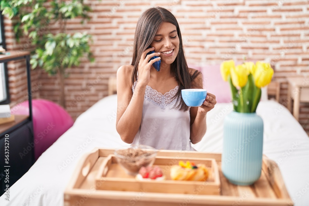 Young beautiful hispanic woman having gift breakfast talking on smartphone at bedroom Young beautiful hispanic woman having gift breakfast talking on smartphone at bedroom