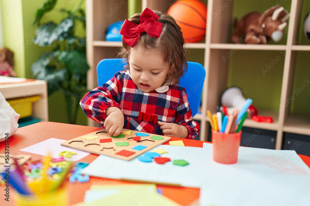 Adorable blonde toddler playing with maths puzzle game sitting on floor at kindergarten Adorable blonde toddler playing with maths puzzle game sitting on floor at kindergarten