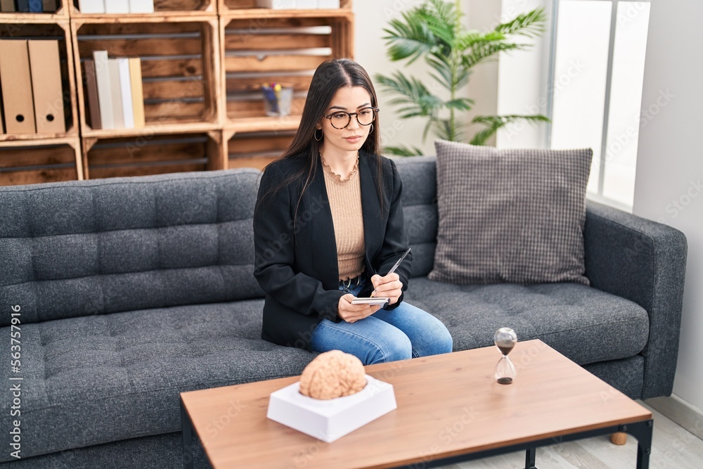 Young beautiful hispanic woman psychologist writing on notebook having therapy at psychology clinic Young beautiful hispanic woman psychologist writing on notebook having therapy at psychology clinic