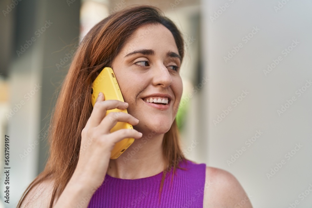 Young woman smiling confident talking on the smartphone at street