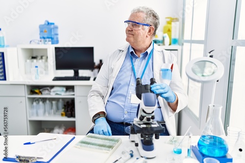Senior caucasian man working at scientist laboratory looking away to side with smile on face, natural expression. laughing confident.