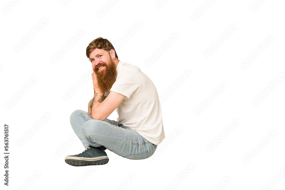 Adult redhead man sitting on the floor isolated