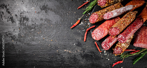 Different types of salami sausage with rosemary and dried chili peppers.