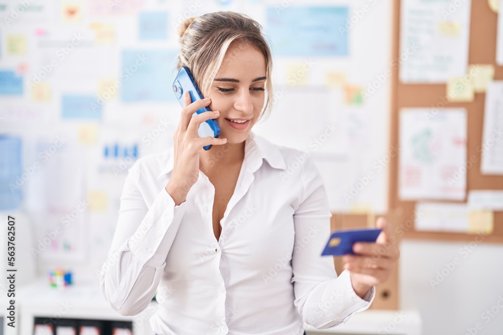 Young blonde woman business worker talking on smartphone holding credit card at office Young blonde woman business worker talking on smartphone holding credit card at office