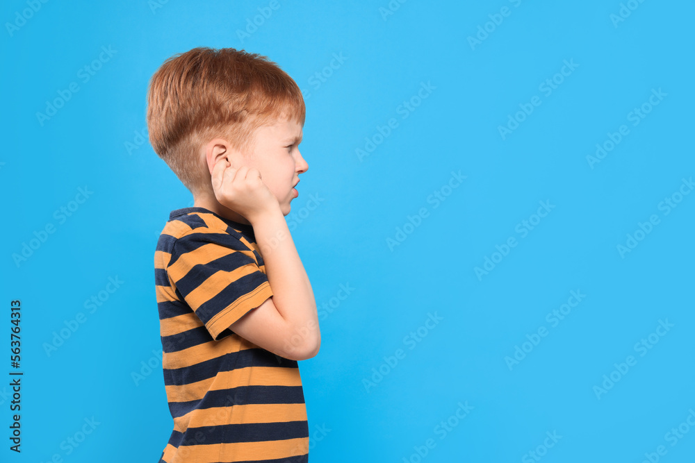 Little boy suffering from ear pain on light blue background. Space for text Little boy suffering from ear pain on light blue background. Space for text