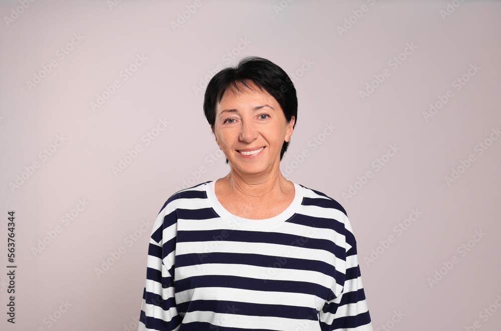 Portrait of smiling senior woman on light grey background Portrait of smiling senior woman on light grey background