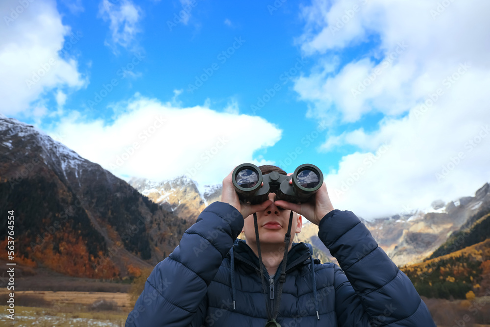 Boy looking through binoculars in beautiful mountains
