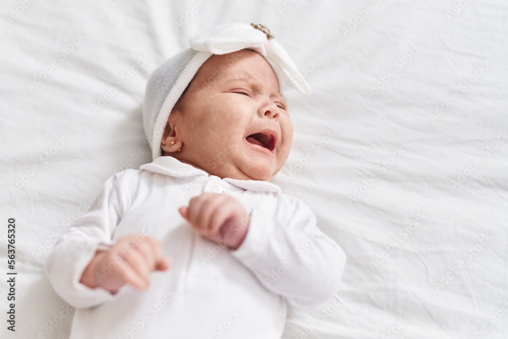 Adorable hispanic baby lying on bed crying at bedroom Adorable hispanic baby lying on bed crying at bedroom