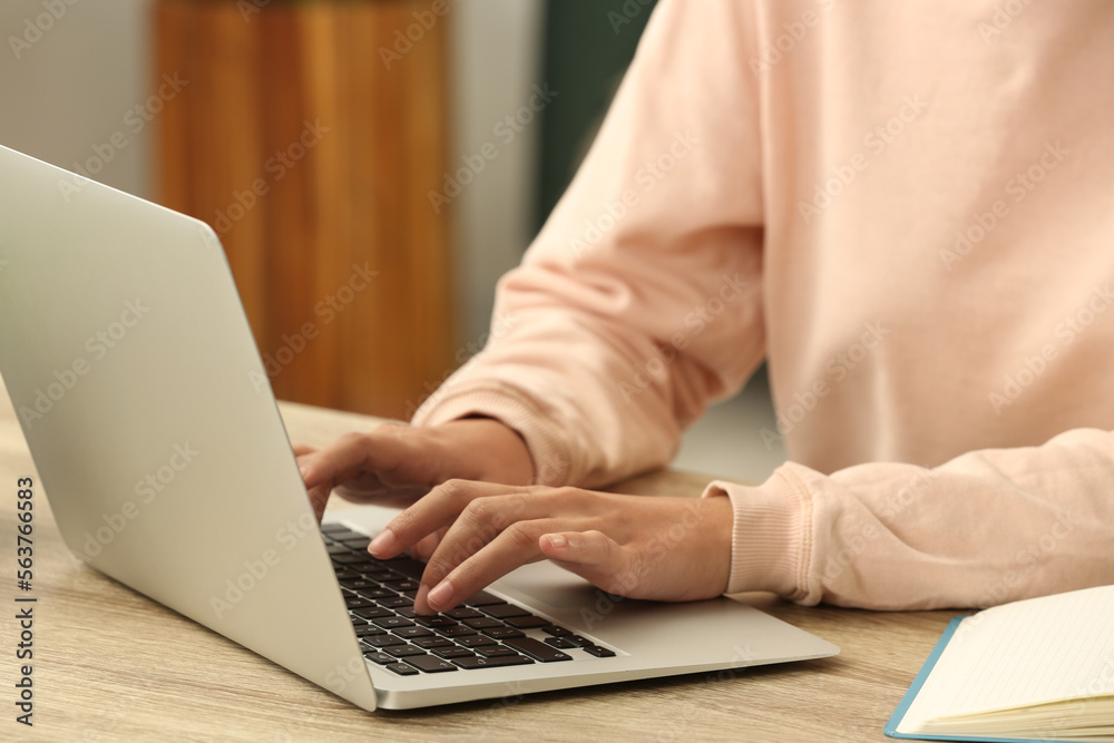 African-American woman typing on laptop at wooden table indoors, closeup African-American woman typing on laptop at wooden table indoors, closeup
