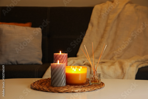 Beautiful candles and reed air freshener on white table indoors. Cosy atmosphere