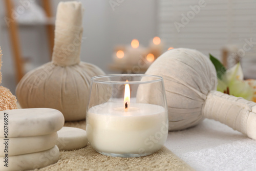 Spa composition with burning candle and herbal bags on massage table in wellness center