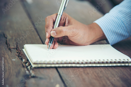 Man hands writing notebook diary with coffee cup and smartphone on wood desk. Close up man hands using pen sitting at wooden table outdoors lifestyle. Men write planner note diary office agenda