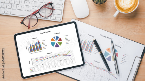 Tablet with charts and reports on office desk workplace. Top view flat lay