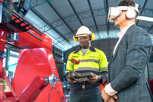 Business man and Factory engineer talking and shaking hands on business cooperation agreementAfrican American male engineer worker using tablet with the automatic robotic machine in the factory.