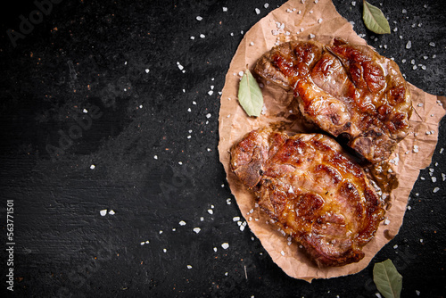 Grilled pork steak on paper with bay leaf. 