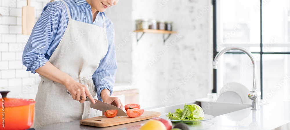 Obraz premium 食事の支度、明るく広いキッチンで野菜を切る