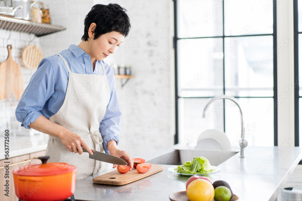 明るく広々としたキッチンで野菜を切っている日本人女性