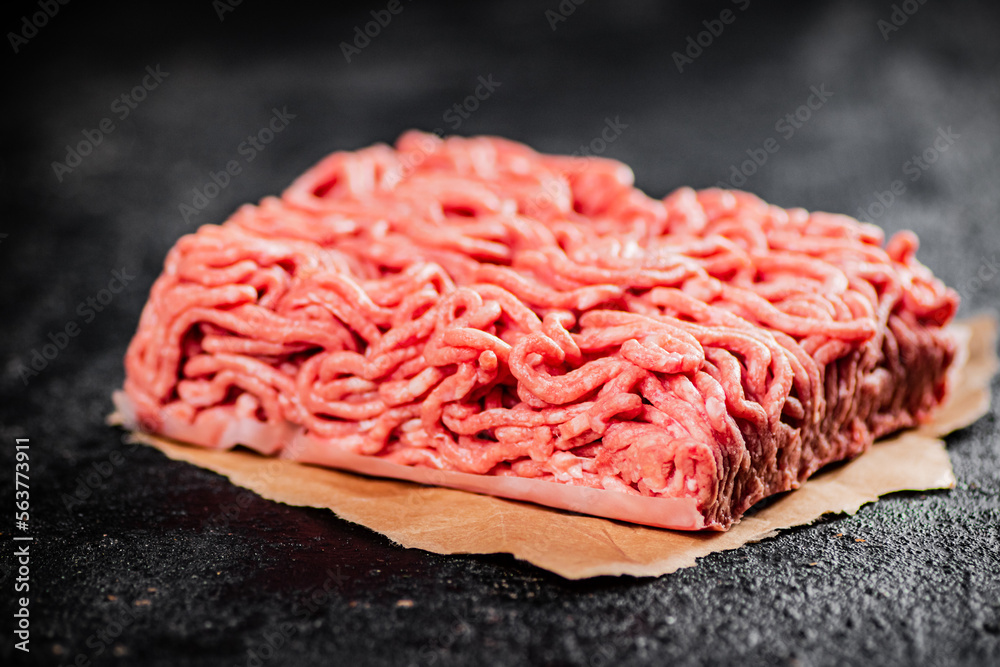 Raw minced meat on paper on the table. Raw minced meat on paper on the table.