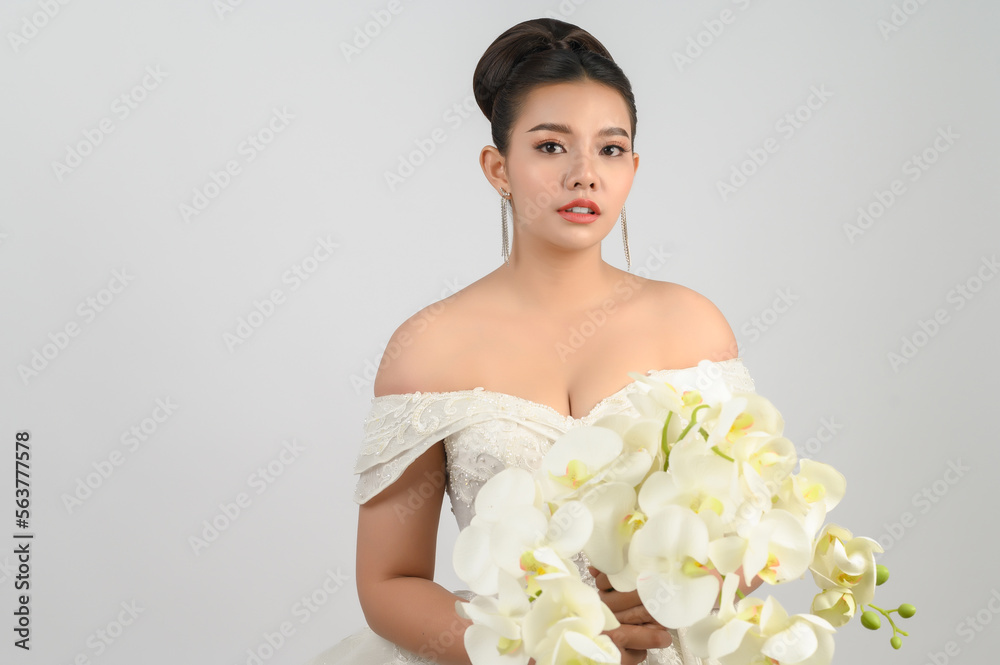 Portrait of beautiful Asian bride in luxurious wedding dress with orchid bouquet Portrait of beautiful Asian bride in luxurious wedding dress with orchid bouquet
