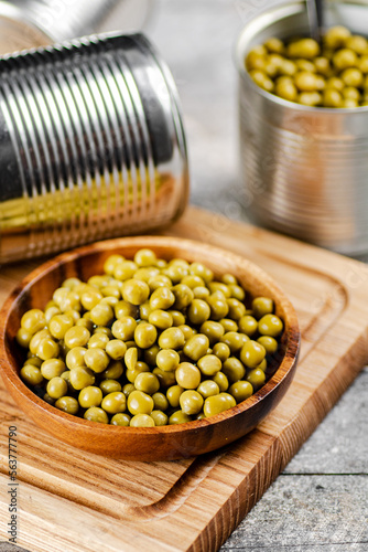 Canned green peas on a wooden cutting board. 