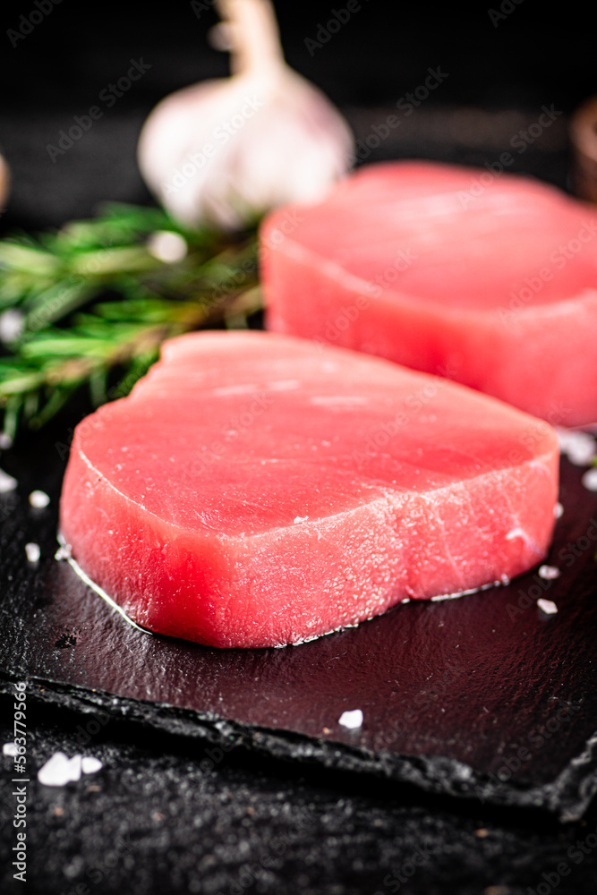 Raw tuna on a stone board with rosemary and garlic. 