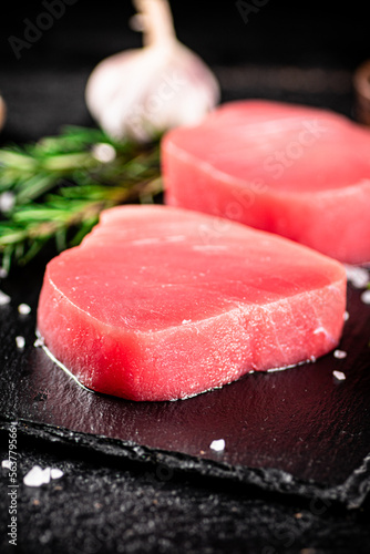 Raw tuna on a stone board with rosemary and garlic. 