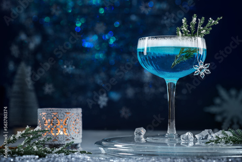 Alcoholic cocktail with gin decorated with a snowflake on a blue background. Cocktail Blue Lagoon. A blue alcohol drink.