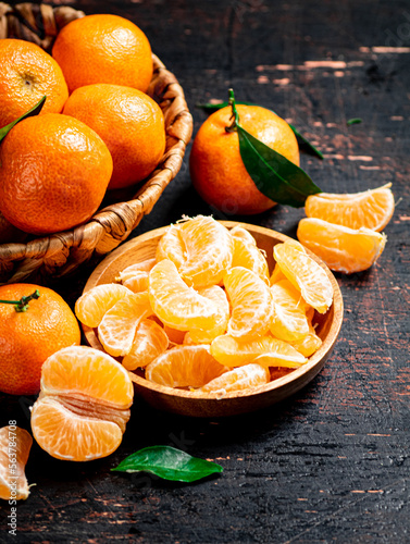 Pieces of fresh tangerines on a plate with leaves. 