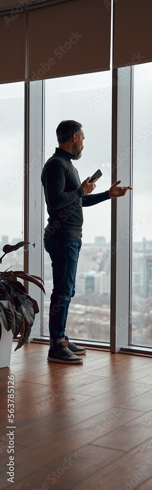 Adult man standing near big window in office space Adult man standing near big window in office space