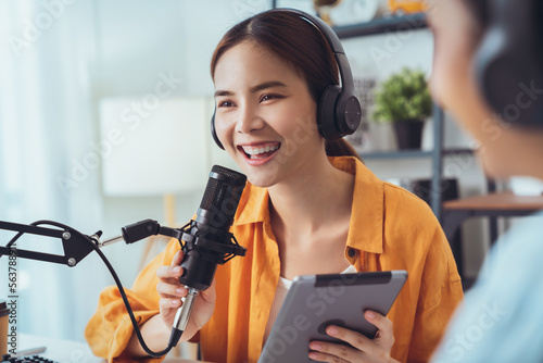Young Asian woman use microphones wear headphones with laptop record podcast interview for radio. Content creator concept.