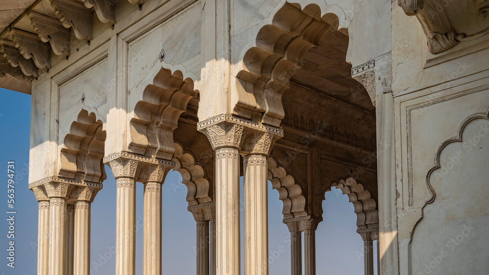 Details of the architecture of the inner palace in Red Fort, Agra. An open hall with white marble columns with carved capitals and graceful arches against the blue sky. India