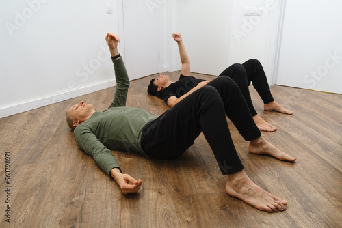 Rehabilitation exercise. Physical therapy concept. Two people laying on the back on the floor with hands and legs up, lymph and blood flow improvement. Feldenkrais method