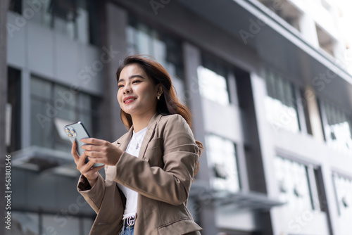 Portrait of young Asian business woman using digital tablet  professional manager holding digital tablet computer using software applications standing in front of modern business building