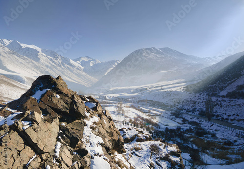 Wintery snow capped mountain in sunny day. Winter landscape with tree under s...