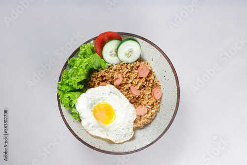 Nasi Goreng Sosis is Fried Rice with Sausages garnished with fresh cucumber and tomatoes slices.
